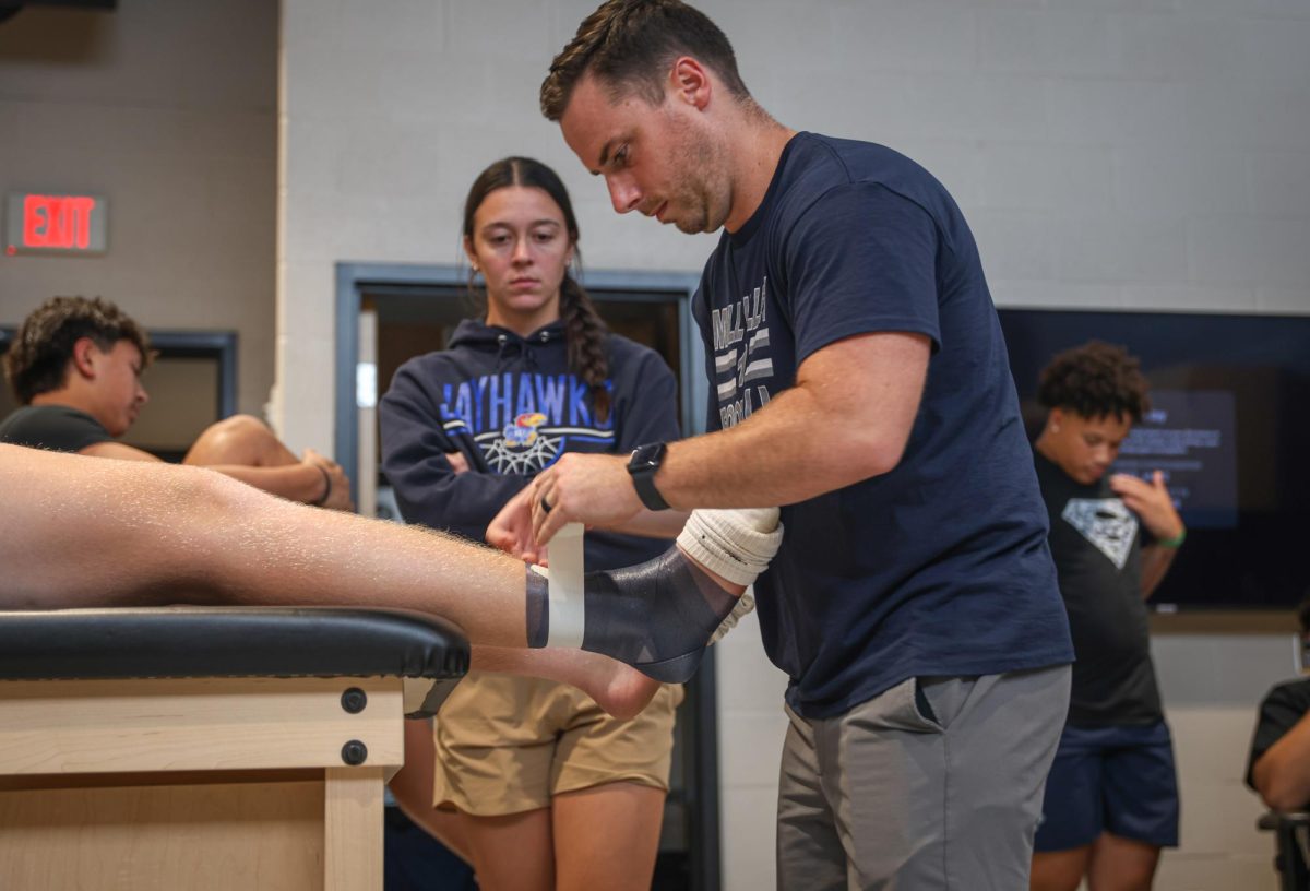 Wrapping a football player's ankle, athletic trainer Jake Brownback helps them prepare for Mill Valley Night Lights Friday, August 30th.  