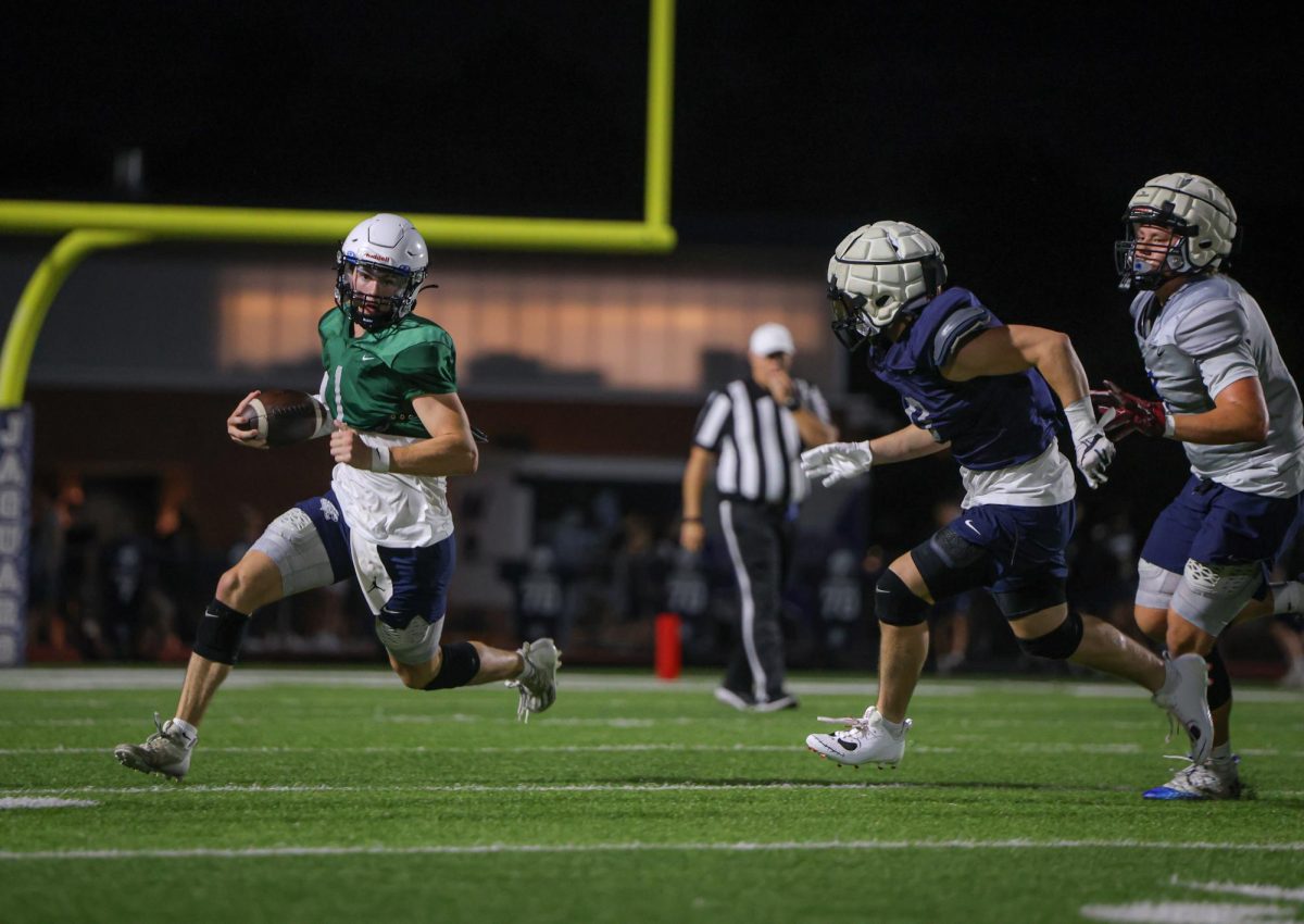 Running towards the sideline, senior Connor Bohon escapes the pressure from the defense. 