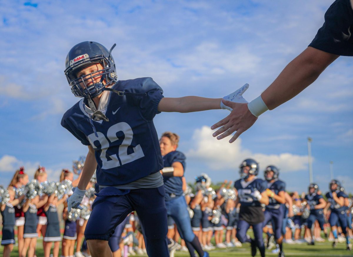 Reaching out his hand, a Junior Jag football player runs through the tunnel before the game. 