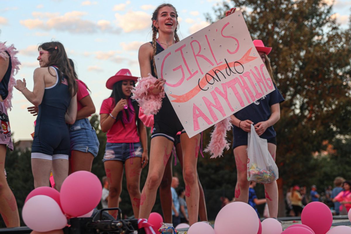 Holding up a sign, junior Finley Rose rides on the girls wrestling float.