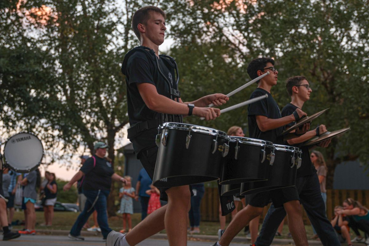 Holding both drumsticks, junior Carson Schmidtlein plays the drums and marches in the parade.