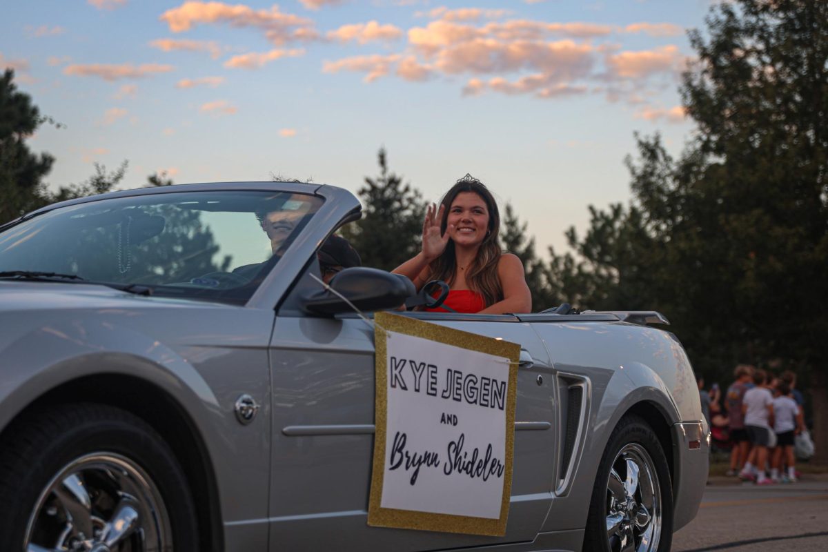 Looking towards the crowd, senior Brynn Shideler waves and smiles at spectators.