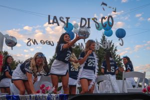 With her hand outstretched, senior Kenzie Johnson stands on the cheer float and throws candy to the crowd.