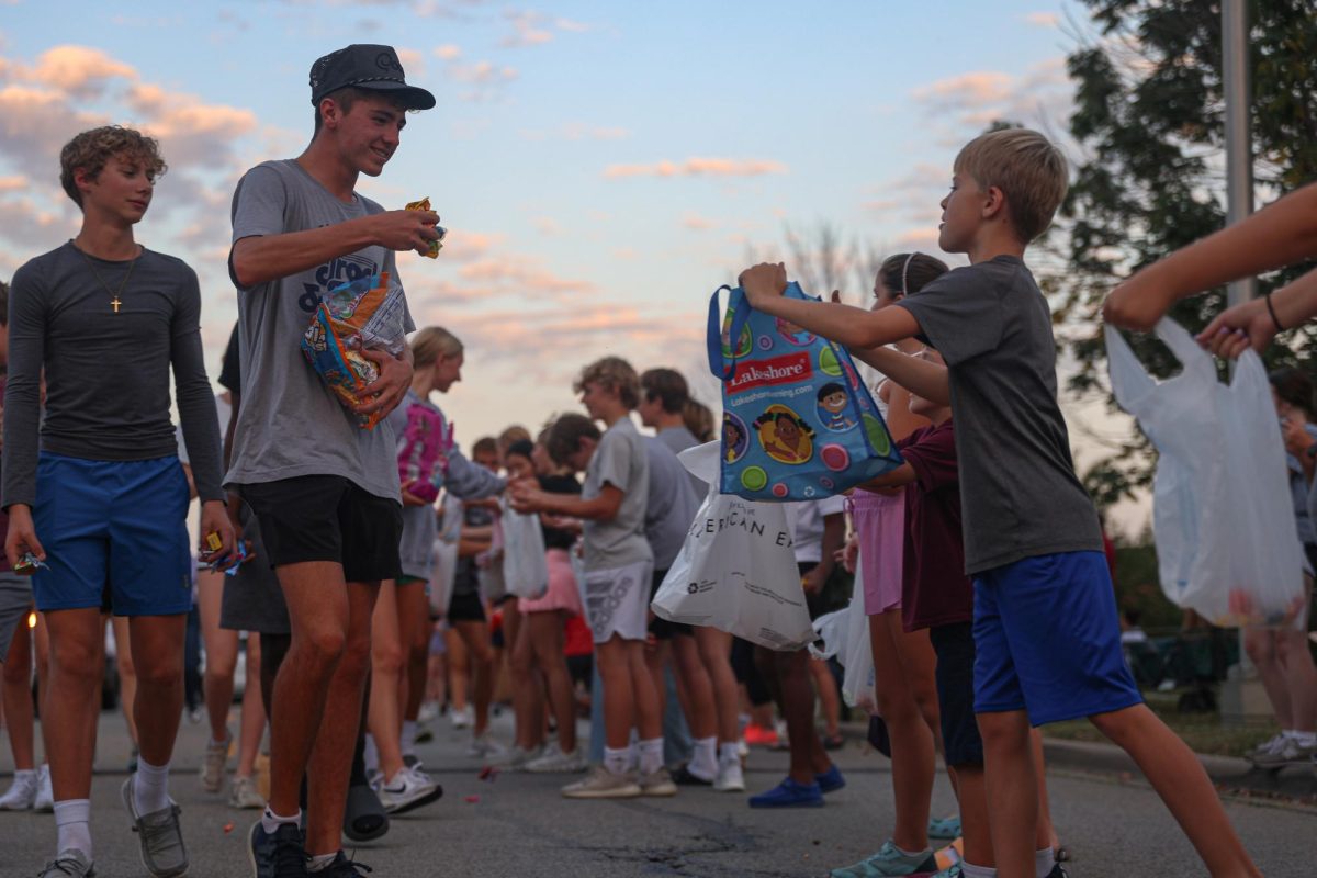 Candy in hand, junior Gus Malone gives candy to a kid along the parade route.