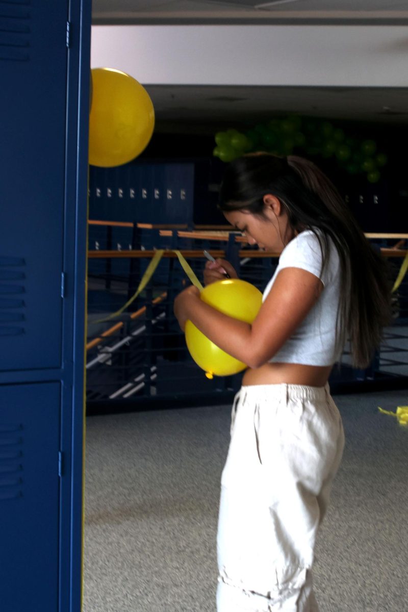 Writing on the balloon, freshman Levi Thatlor decorates lockers.
