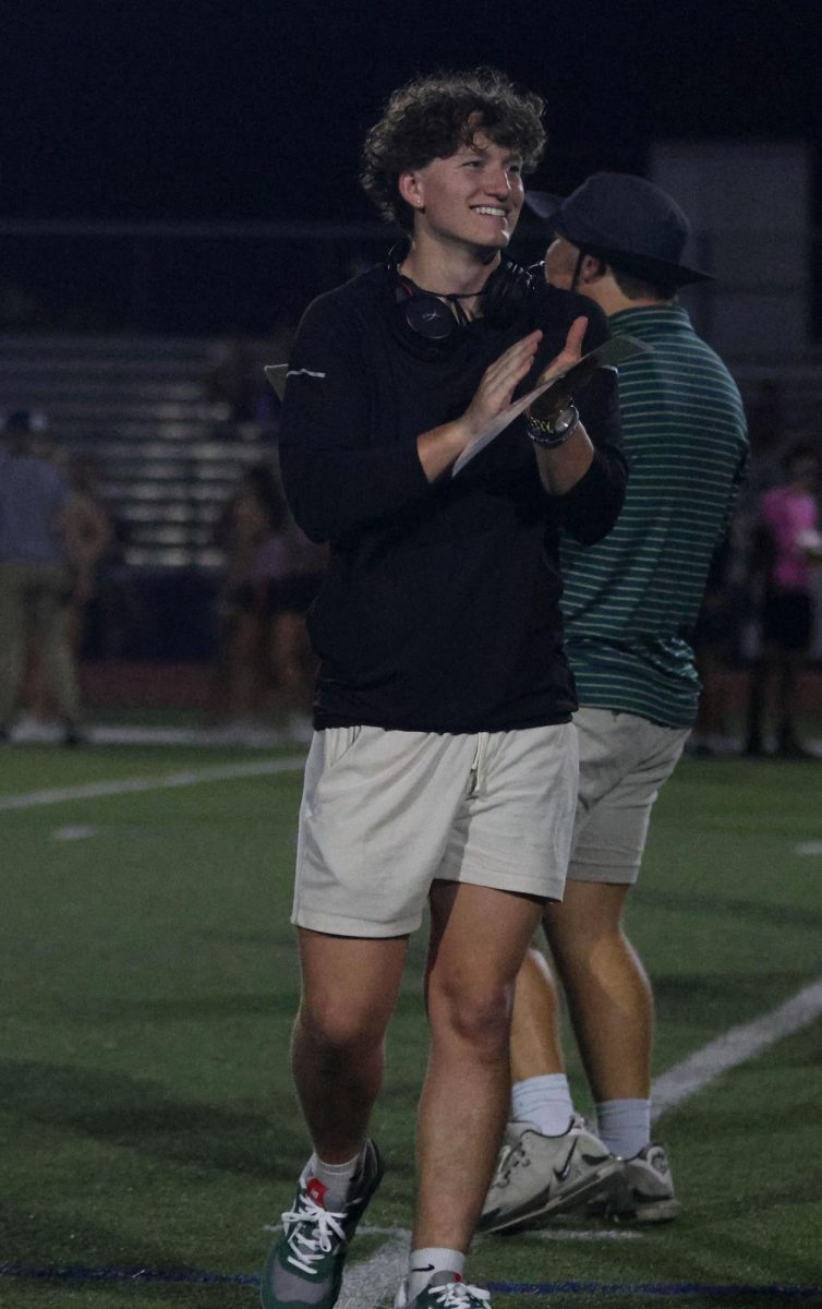 Powderpuff coach senior Kye Jegen smiles and claps after seniors make a good play.
