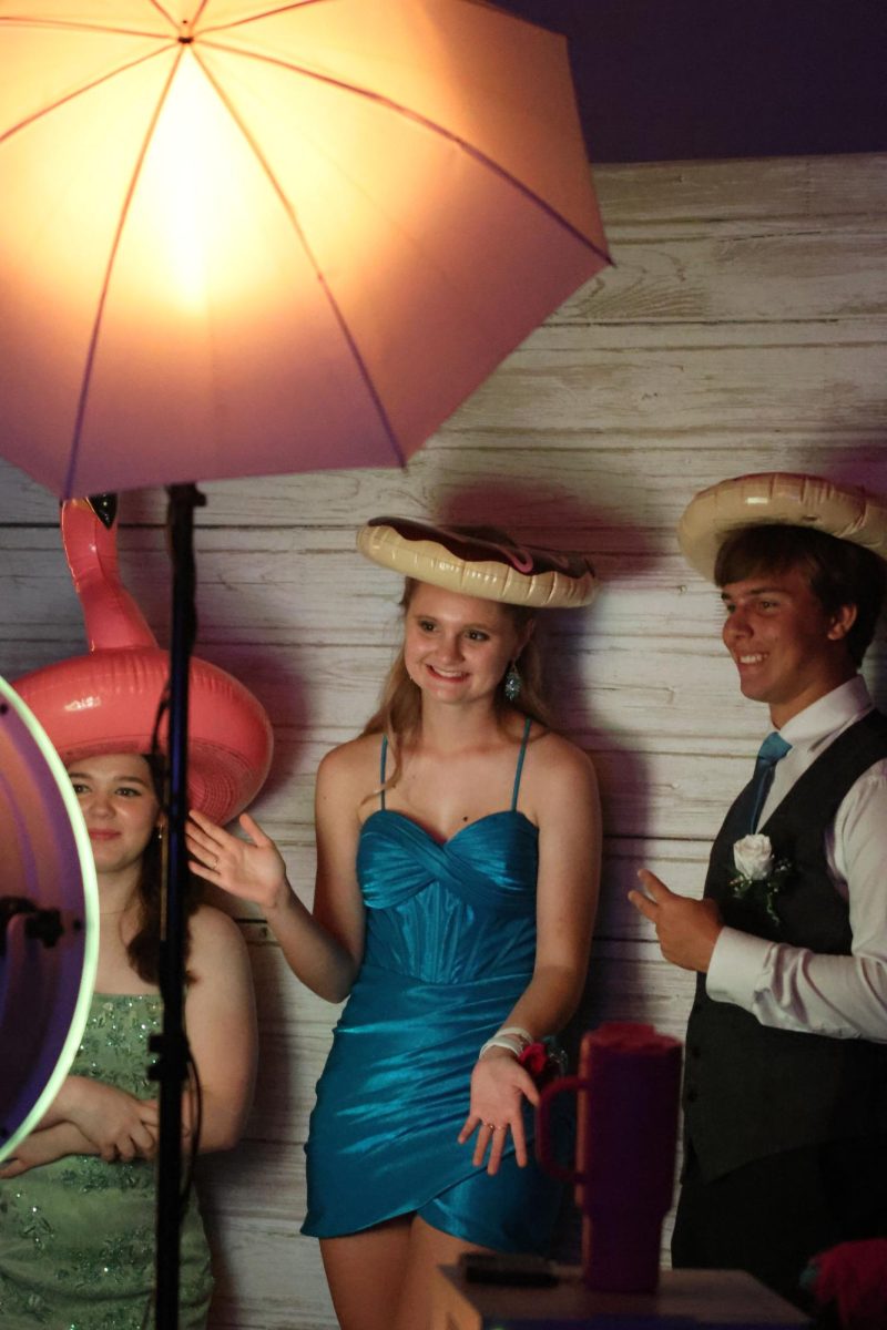 While in the photo booth, seniors
Jenna Newman, Marrisa Akehurst and junior Jack Thomas wear props for their photos