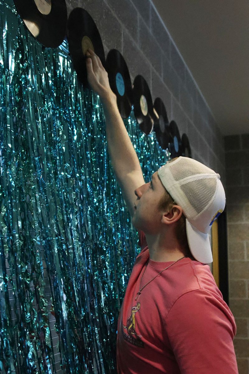 Staying in theme, senior Logan Koester tapes a disc to the wall. 