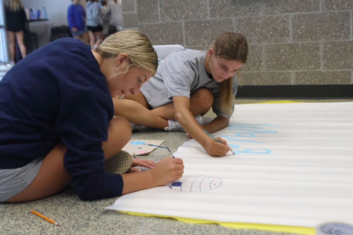 Painting a banner, seniors Remi Ziebell and Kate Martin work together. 