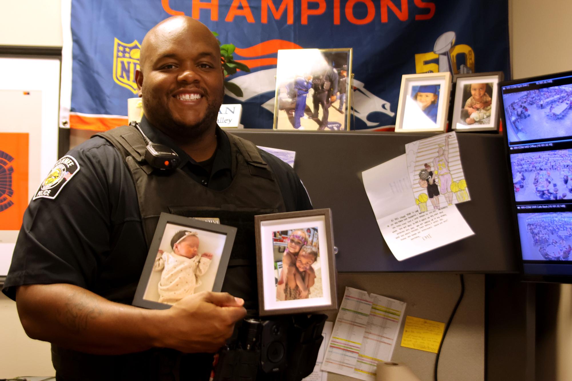 SRO Officer Darion Hillman poses with pictures of his three daughters. 