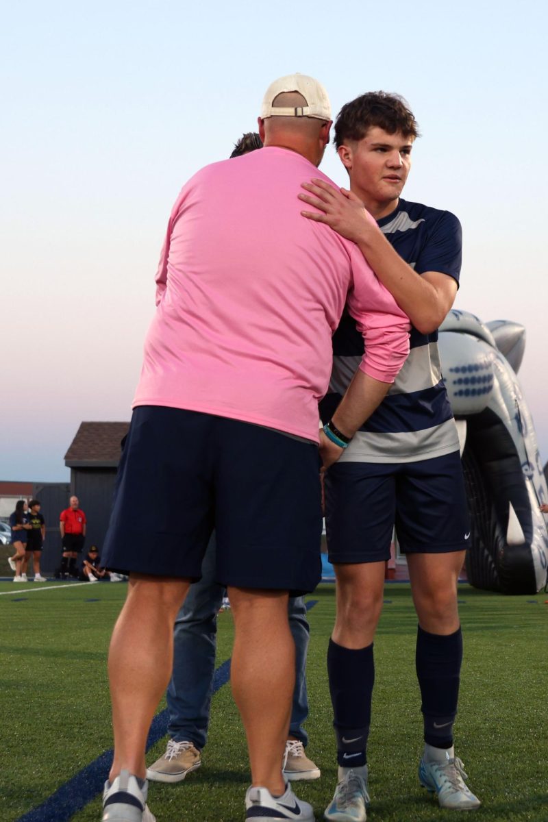 During the senior night recognition, senior Joel Hayes hugs assistant coach Justin Crawford.