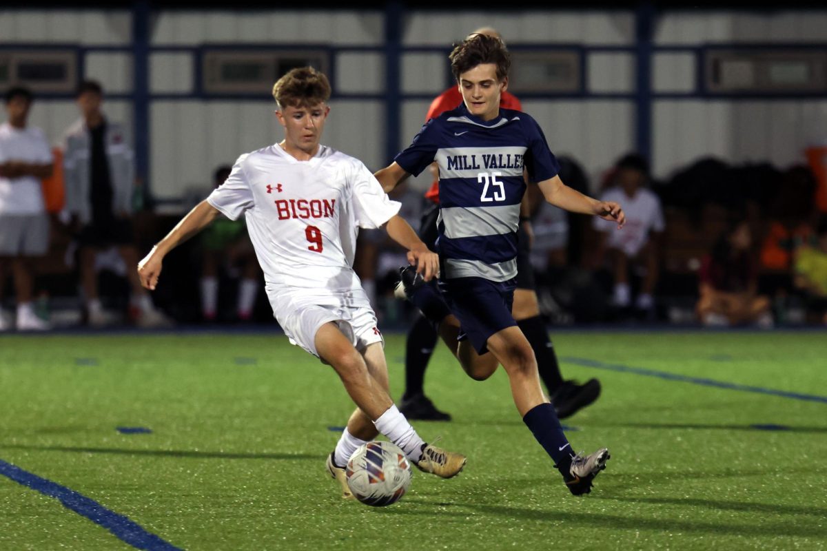 Striding, sophomore Brice Zenger attempts to take the ball from his opponent.