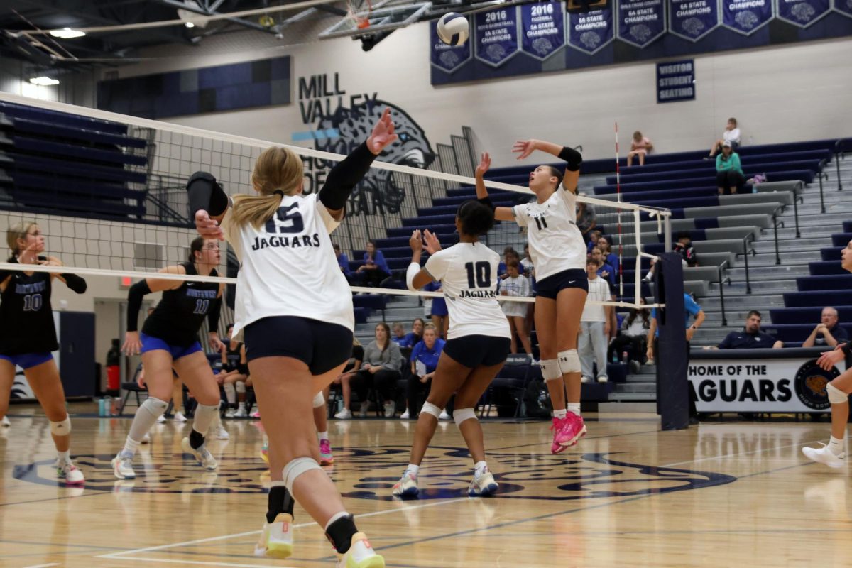 Junior Ella Florez prepares to set the ball while junior Leilah Perry and Josie Danielson prepare to spike.