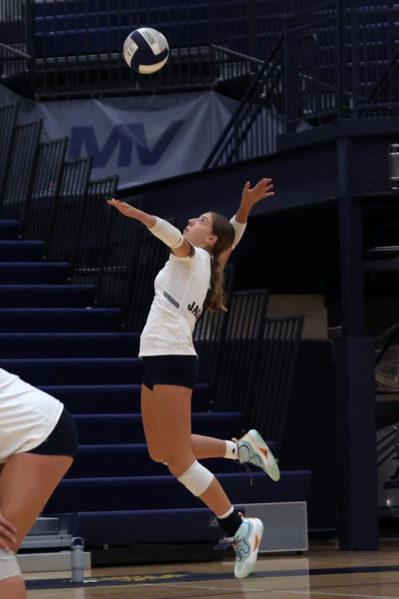 Freshman Ellie Bain jumps to serve the ball.