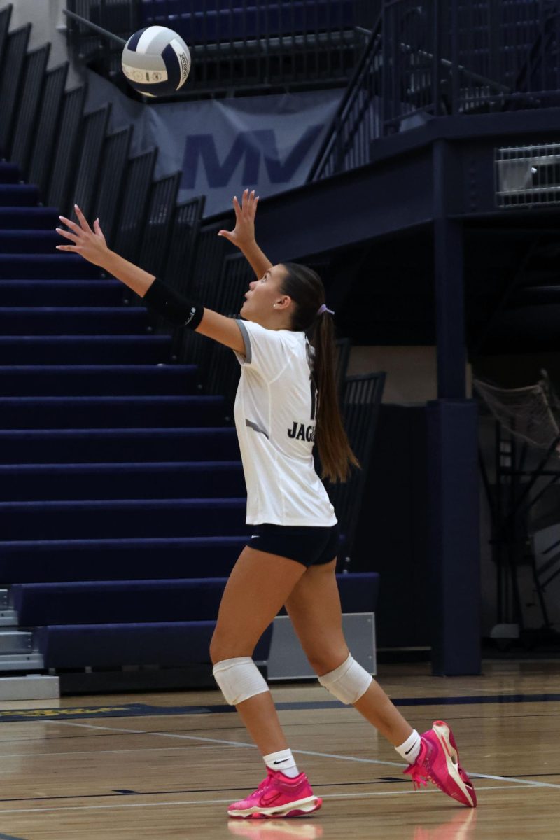 Looking upwards, junior Ella Florez prepares to serve the ball.