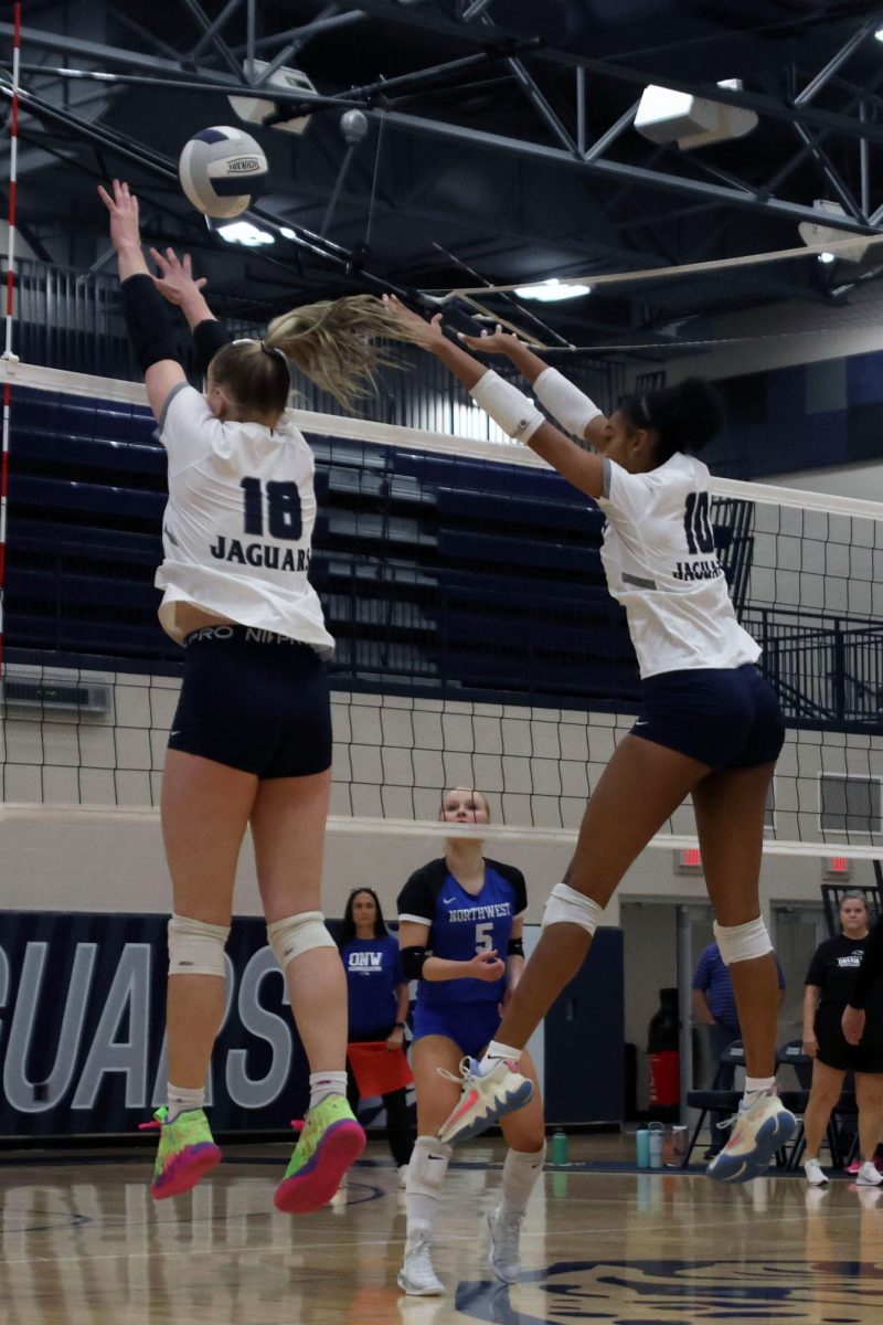 Sophmore Riley Riggs and junior Leilah Perry jump up to block the ball.