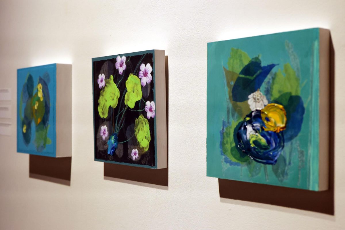 Paintings of flowers are displayed in a gallery.