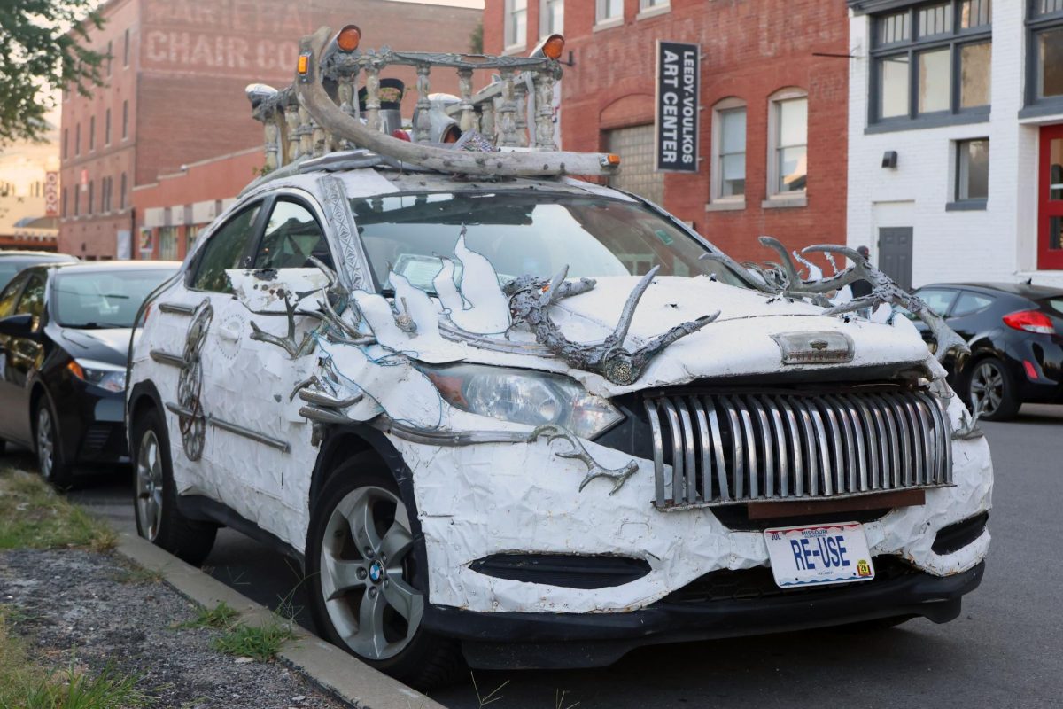 Car, turned into art through metal, paint and sculptures, is parked at the event. 