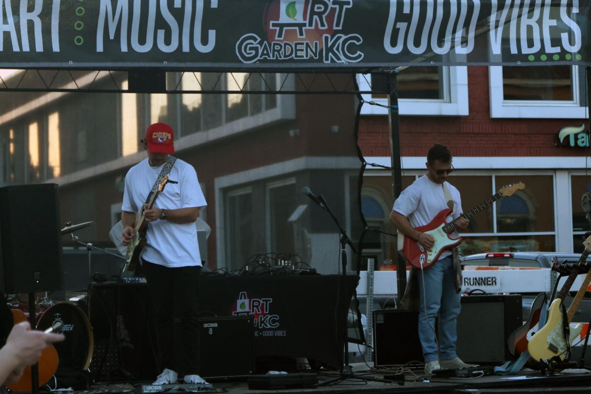 Musicians tune their guitars before their live music performance near art vendors. 