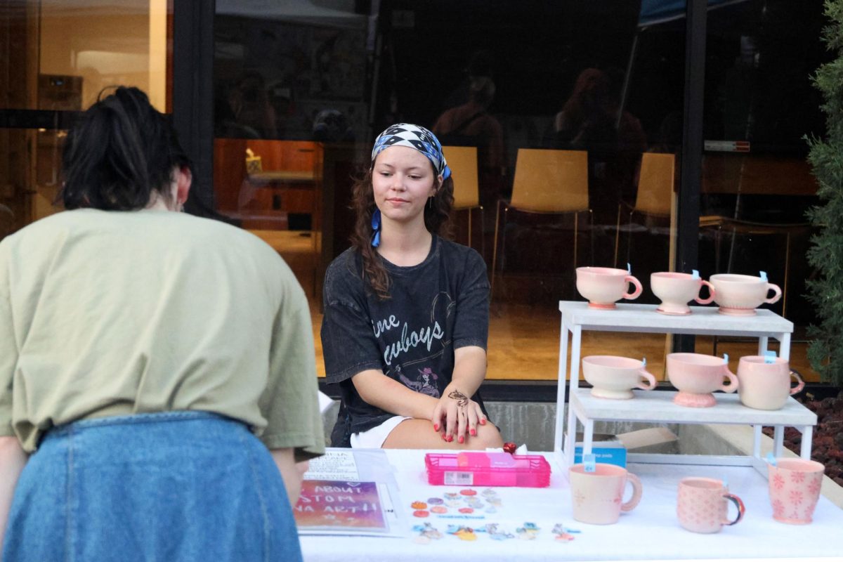 Art seller watches as a customer looks through her sculptures deciding what to buy. 