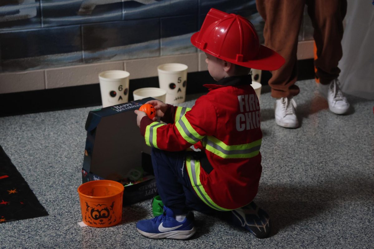 Dressed up as a firefighter the member of the community picks his prize from participating in ring toss. 