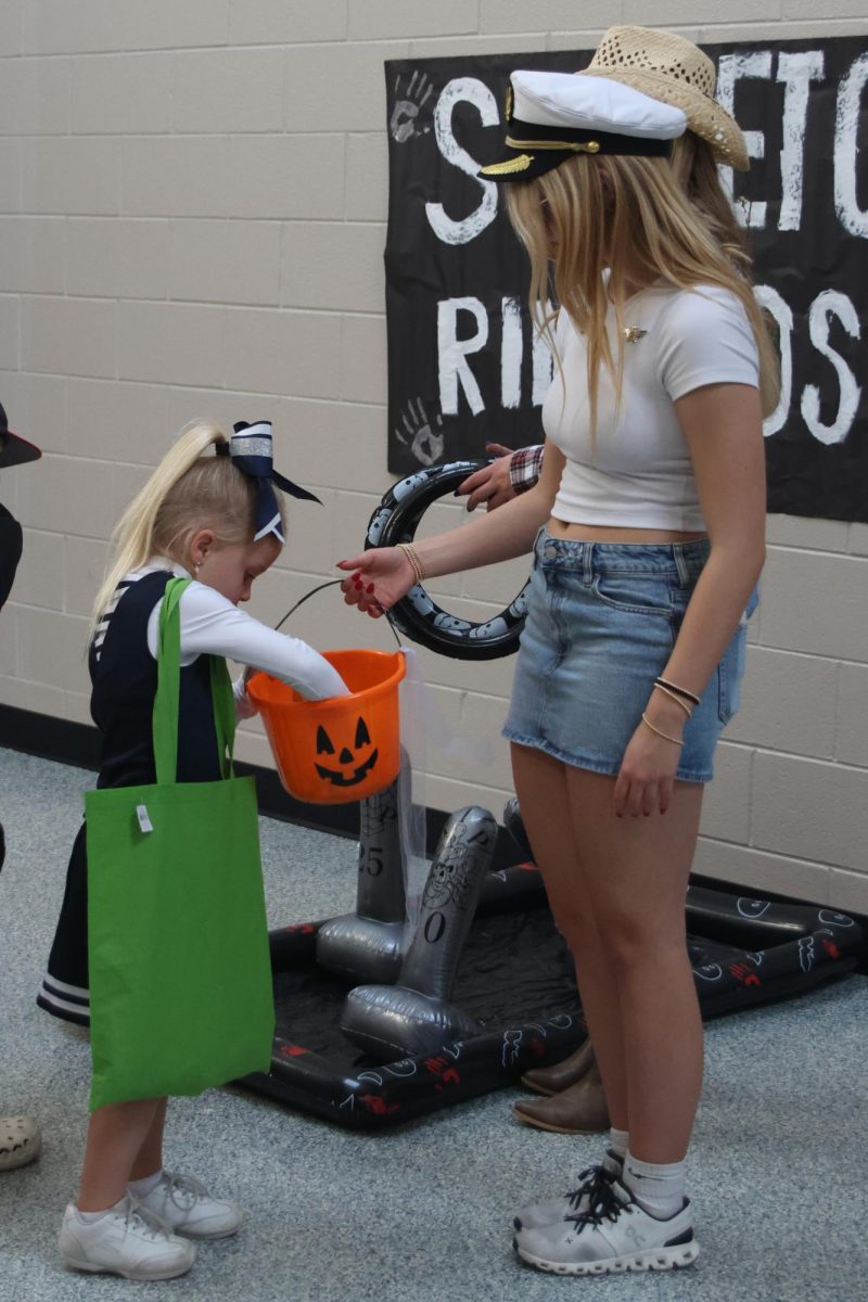 Junior jag cheerleader wins candy out of junior Claire Cooper halloween bucket. 