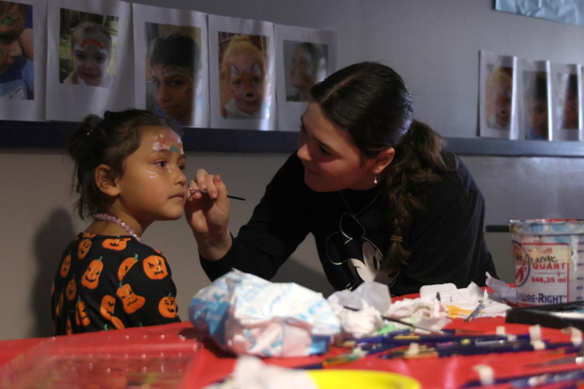 Paintbrush in hand, NAHS member senior Jenna Newman paints a rainbow on one of the Haunted Hall participants face. 