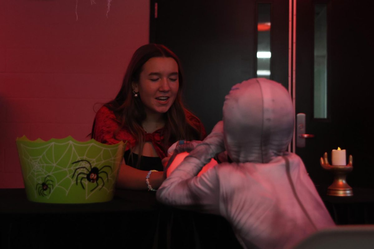 Hand on the magic ball, Avery Royer tells the trick-or-treater his fortune. 