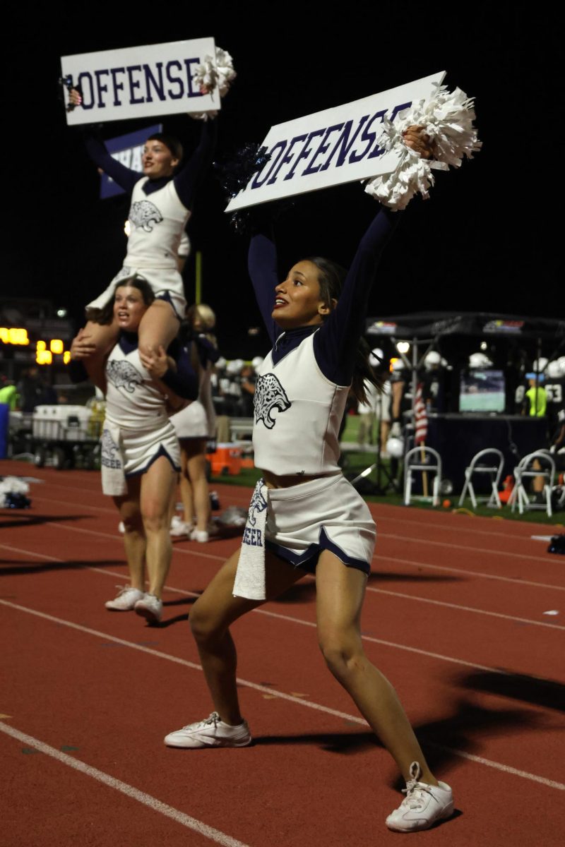 Holding a sign, senior Jada Winfrey cheers “OFFENSE” to the student section.
