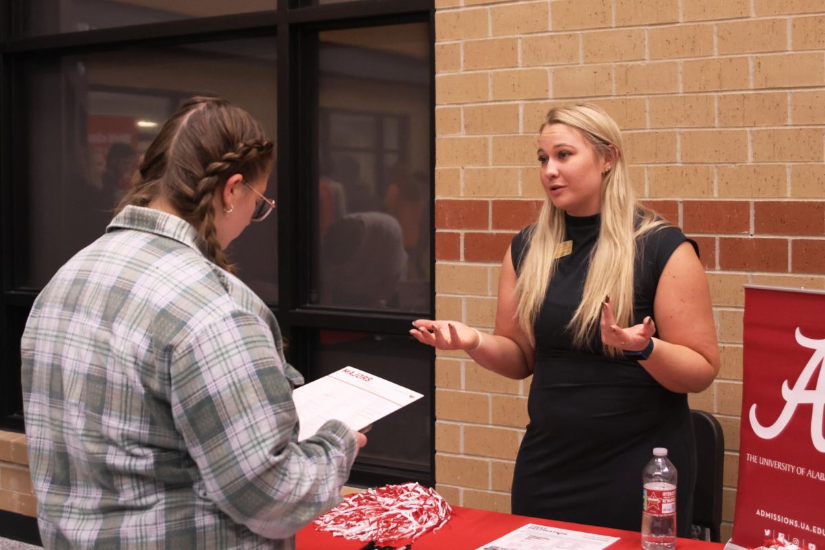 A representative from The University of Alabama gives a pamphlet to Junior Liberty Bouskill.