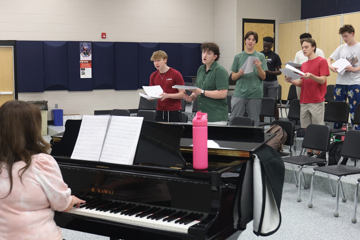 Choir teacher Laura VanLeeuwen plays piano as the boys learn their harmonies for the opening number.