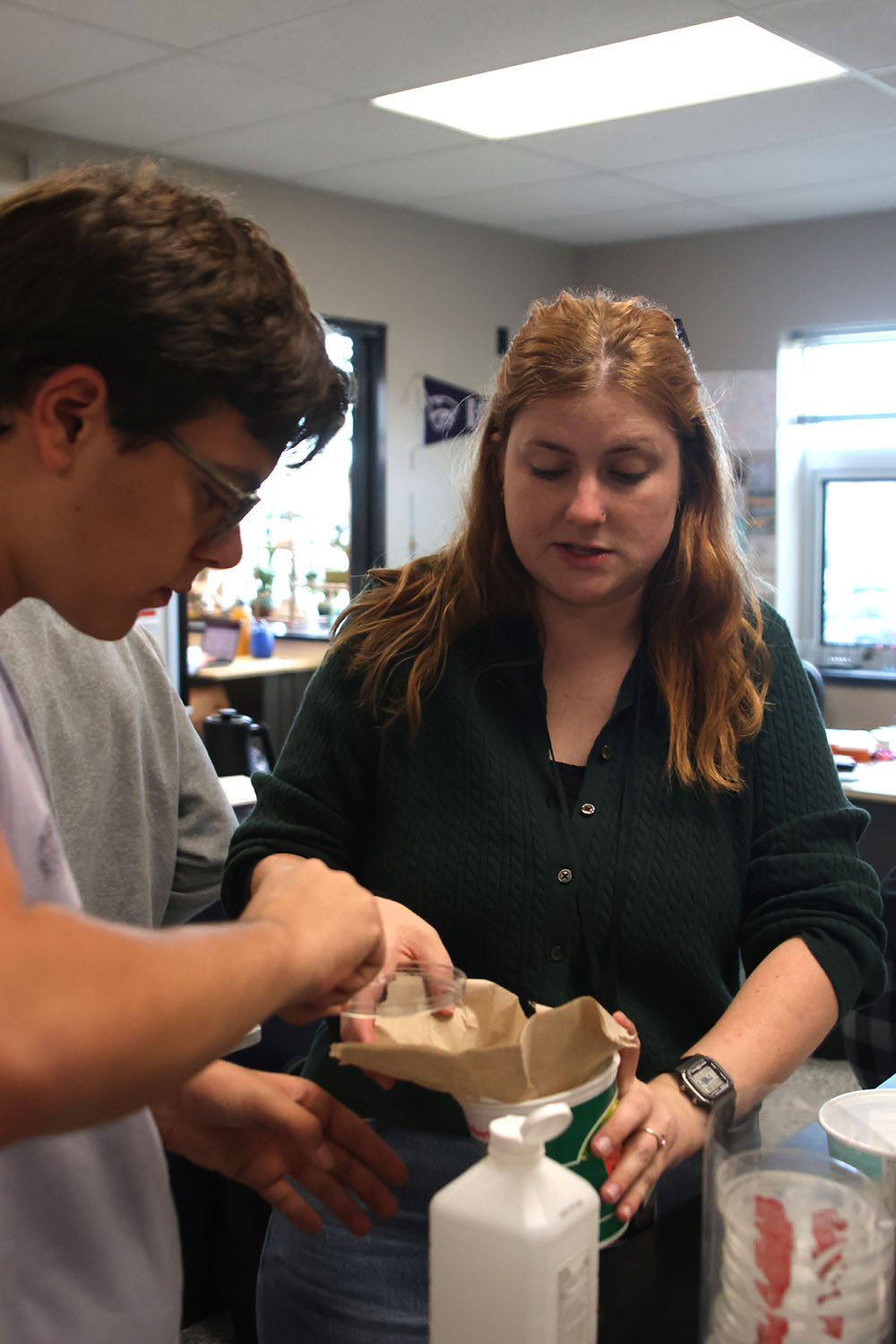 Science teacher Caroline Gambill helps students set up relaxing chambers for the dead bugs.