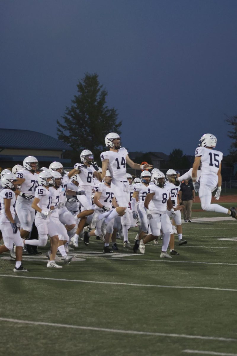 Leaping in the air, seniors Andy Watts and Connor Bohon celebrate the coin toss with the rest of the team. 