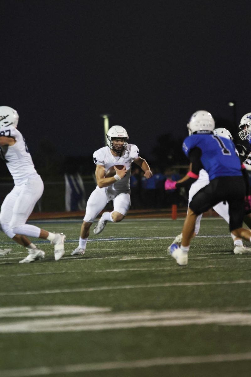 Trying to avoid the opponents, senior Connor Bohon runs around them. 