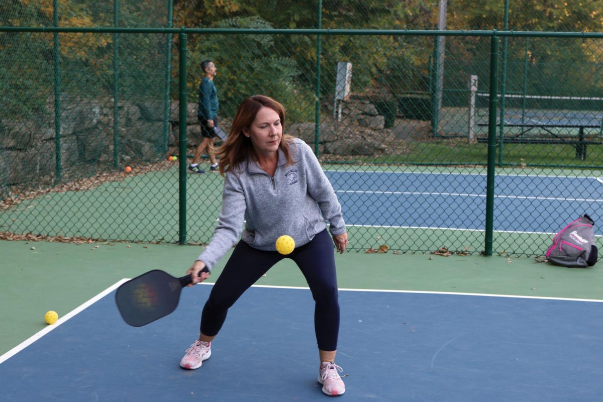 Teacher Jennifer Dillon prepares to serve the ball across the court on Monday, Oct. 14.  