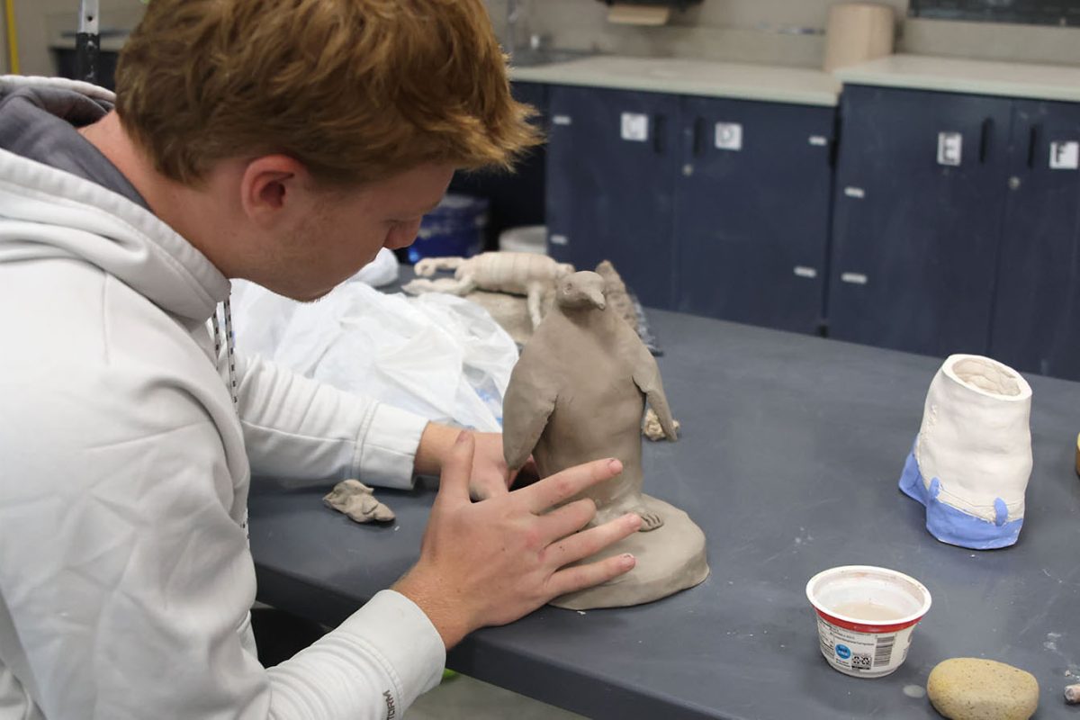 Senior Connor Wood adds more clay to fix his penguin sculpture.