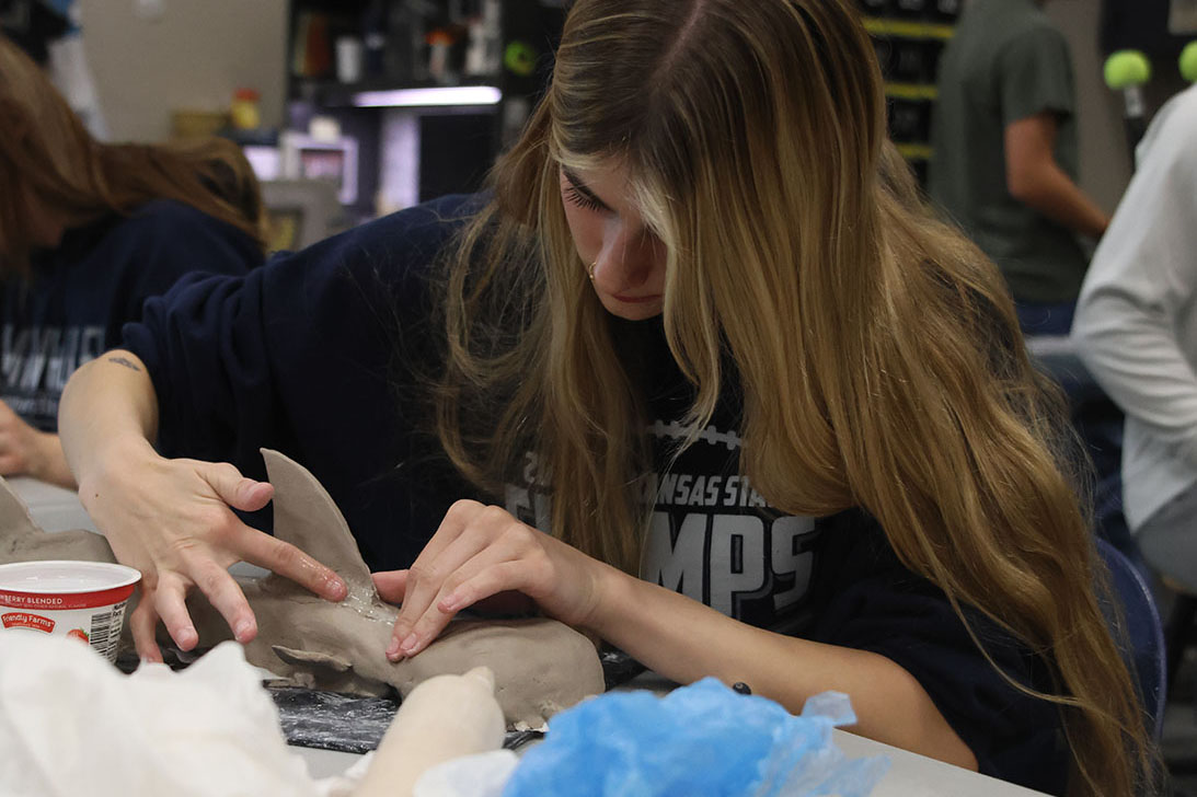 Junior Finley Rose uses her fingers to smooth out her shark sculpture with water.