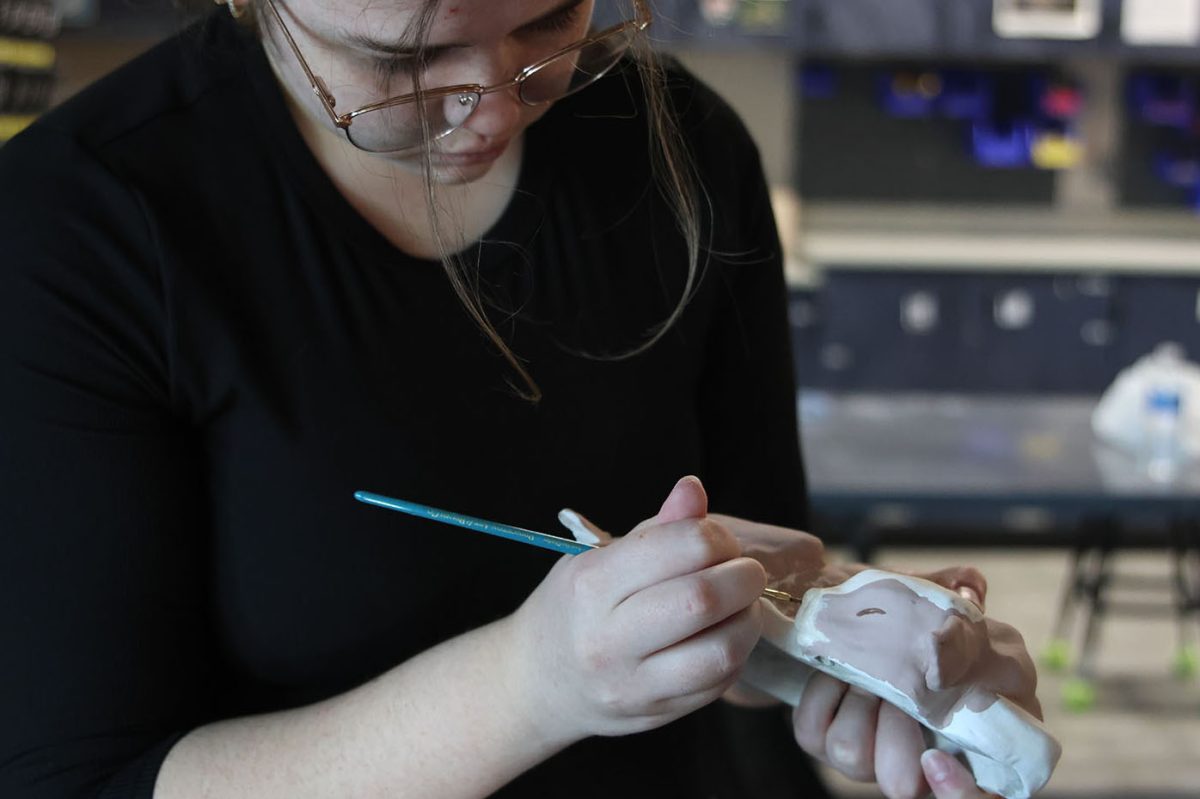 Senior Lani Fagen adds finishing touches as she paints her finished cow.