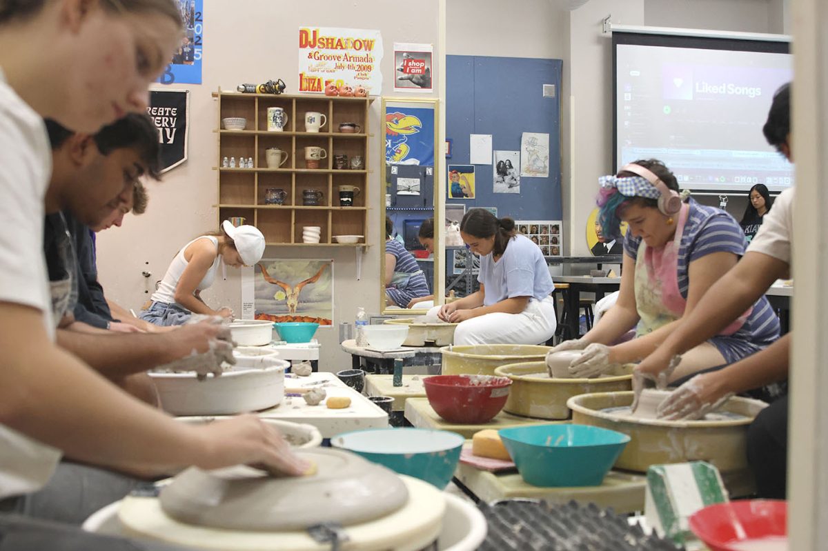 A group of students practice throwing on the wheel to show off their bowl making skills.