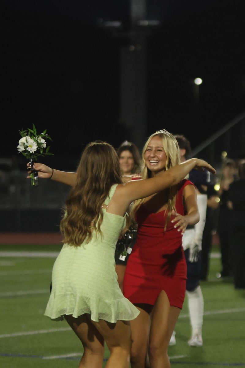 Senior Maggie Wieland is awarded with a tiara and sash as well as a hug from 2023 Homecoming Queen Lucy Roy for winning 2024’s Homecoming Queen.