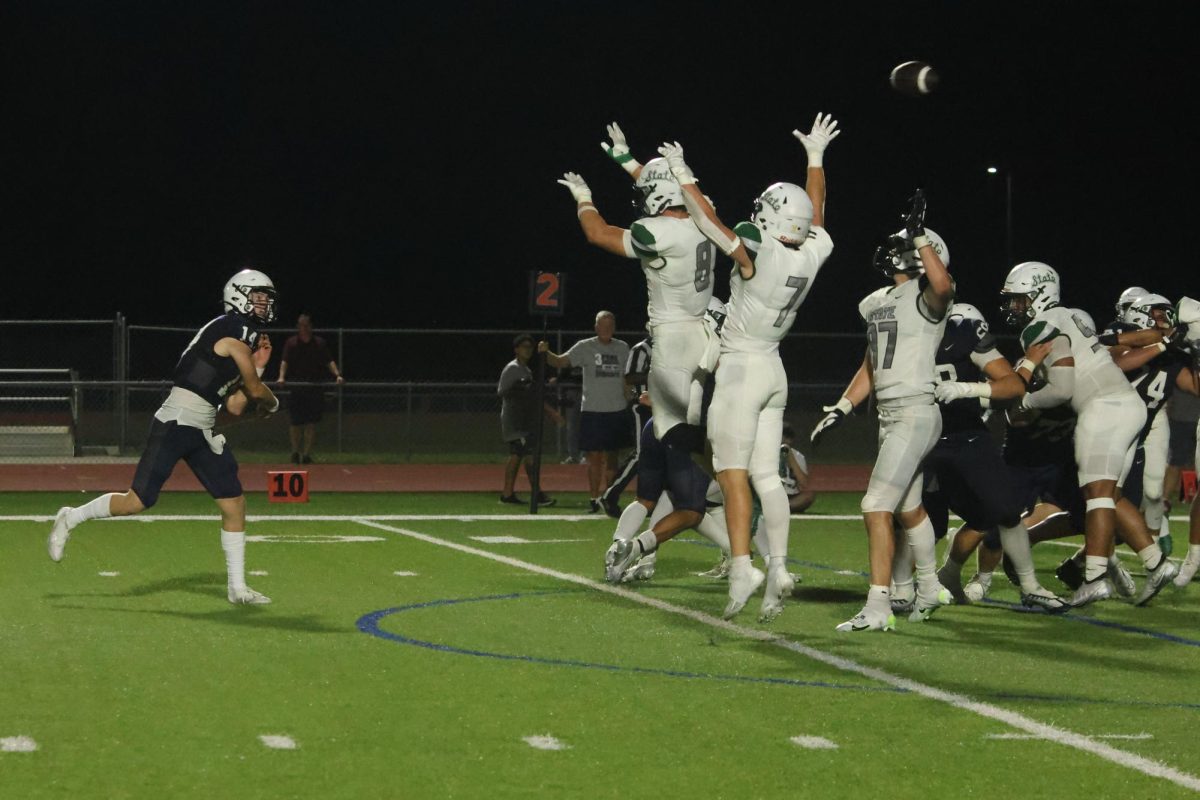 Still going for the pass, senior Connor Bohon throws the ball over several opposing players, successfully making the pass complete.