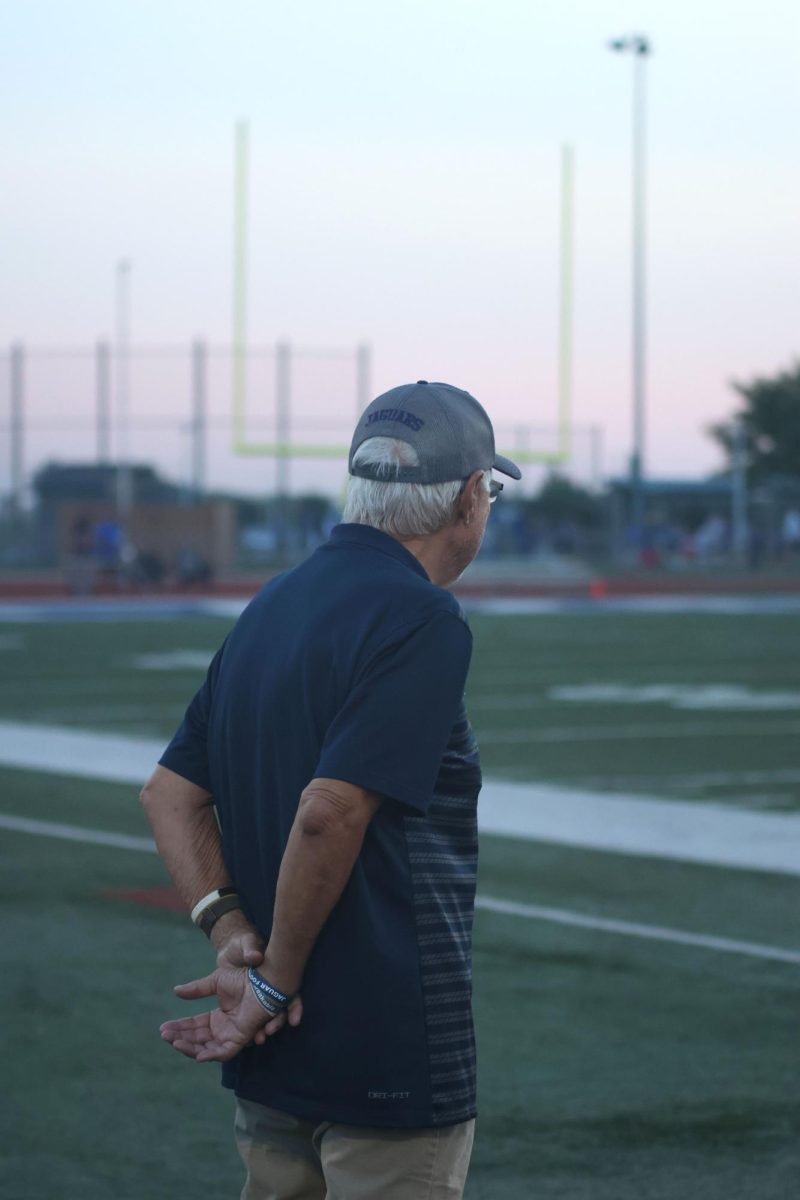 Coach ... watches the team warm up before the game.