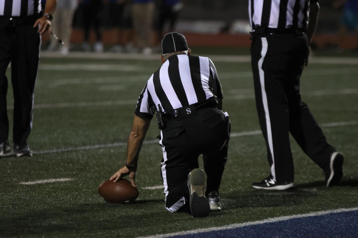 A ref holds the ball for it to be measured.