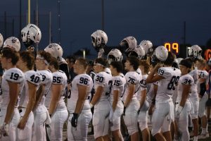 Mill Valley football players hold their helmets high as they get ready for kickoff before the game against Gardner Edgerton Friday Oct. 11. 