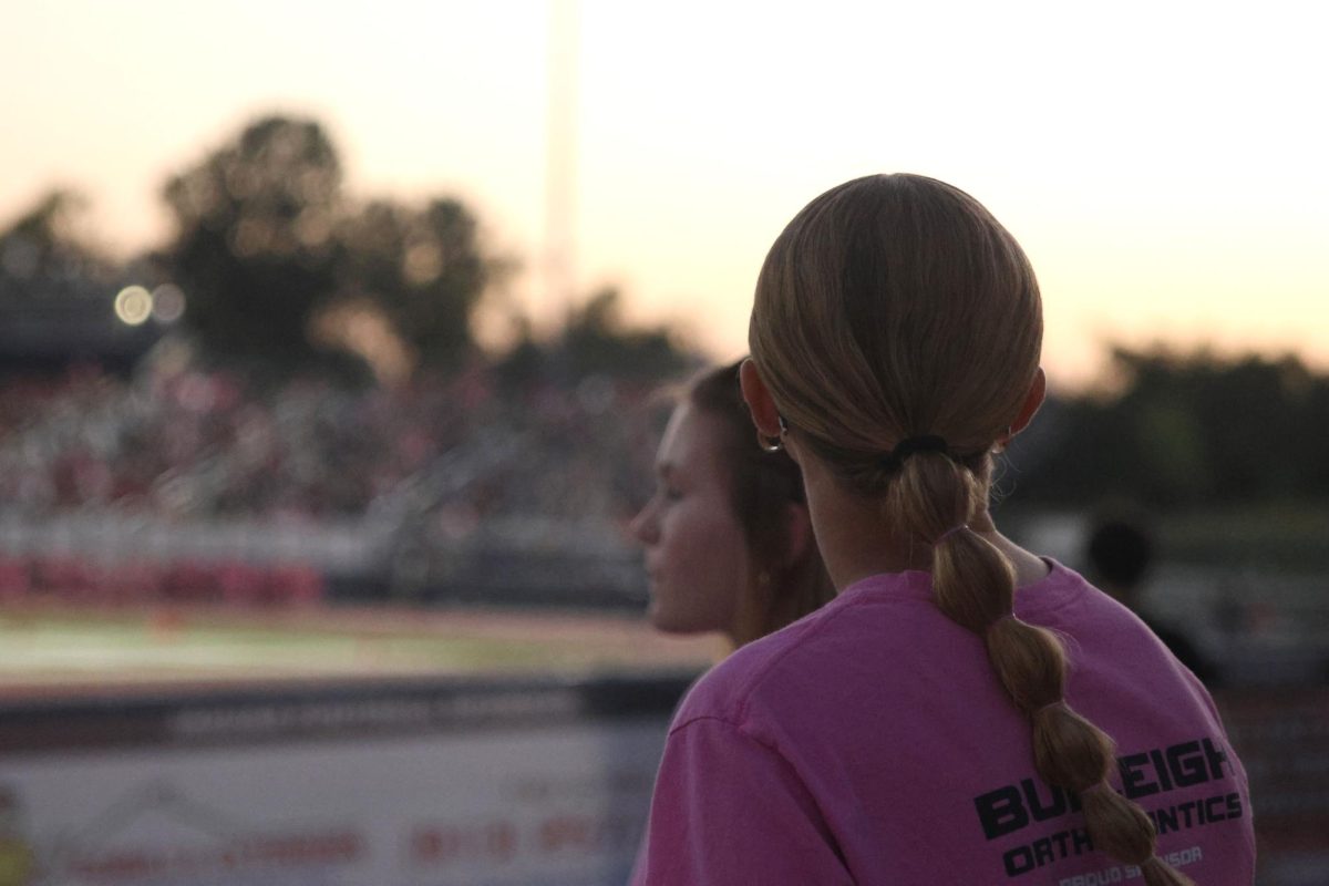 Looking out into the crowd, freshman Logan Stafford watches the football game.