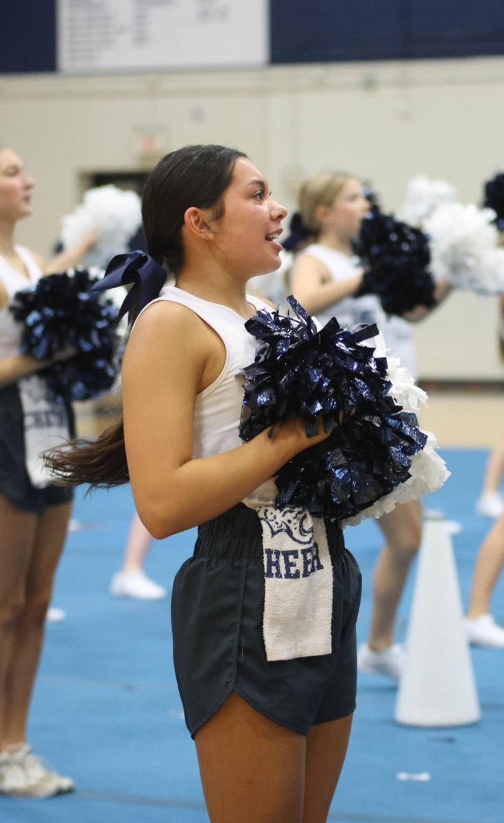 With her arms in front of her, junior Stella Beins cheers towards the stands. 