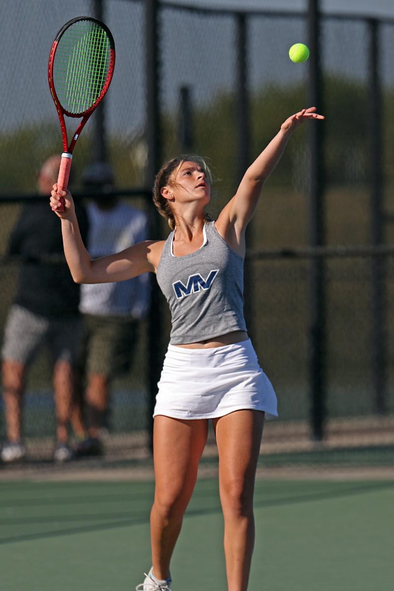 Arms up, senior Marissa Hoelting serves to her opponent.