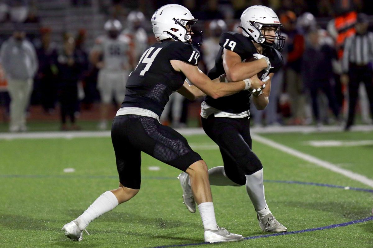 Senior Connor Bohon hands off the ball to sophomore Max Piva in a play against Olathe East. 