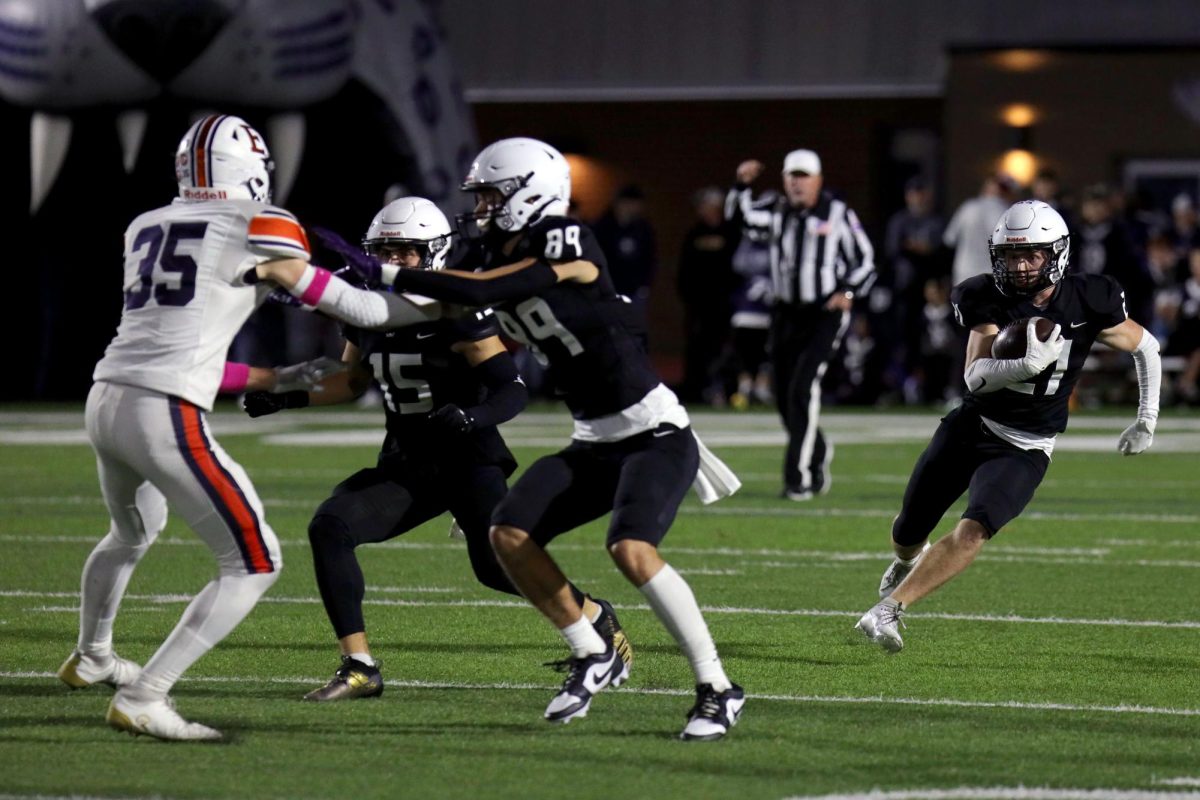 Senior Andy Watts and junior Reece Riedel defend senior Clayton Sondgeroth as he makes a run for the endzone.