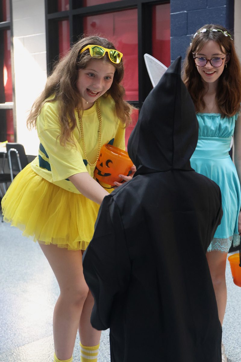 With a smile, freshman Ava Munsey compliments the kid's costumes and gives them candy.